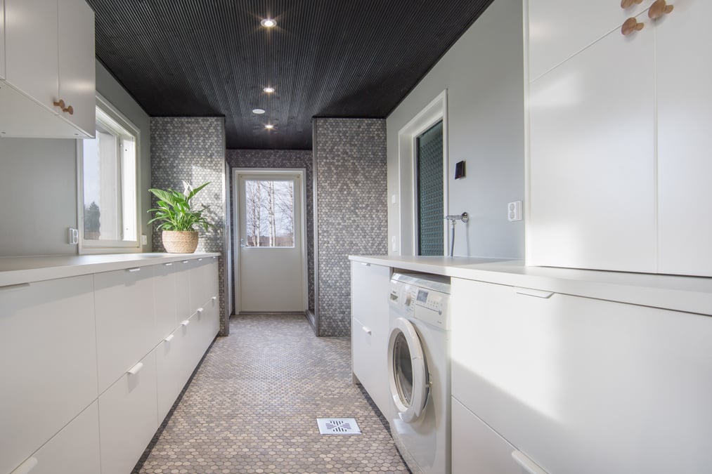 Valoisa ja vaalea kodinhoitohuone mosaiikkilaatoilla