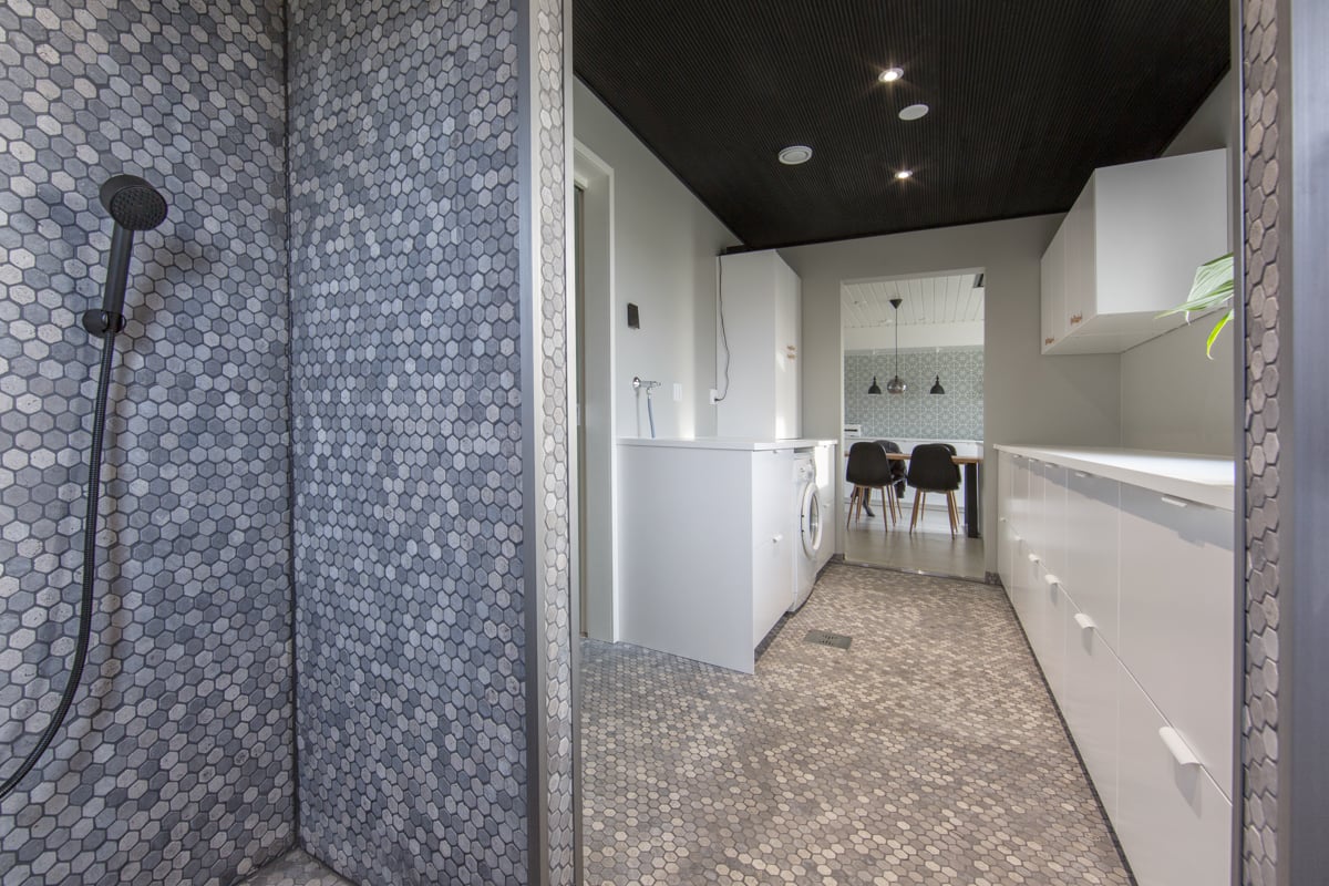 Kodinhoitohuoneessa mosaiikkilaatta ja valkoiset kaapit