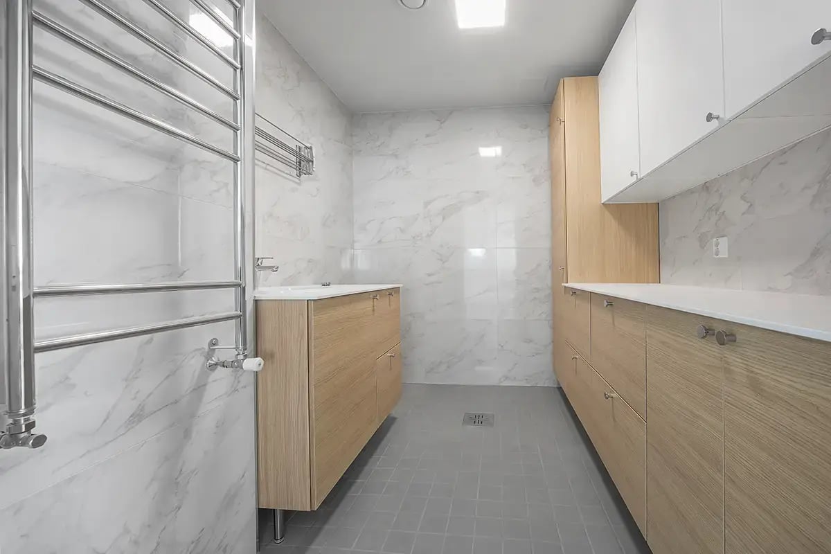 Uusi kodinhoitohuone, marmorikuvioiset seinälaatat ja vaaleat kalusteet