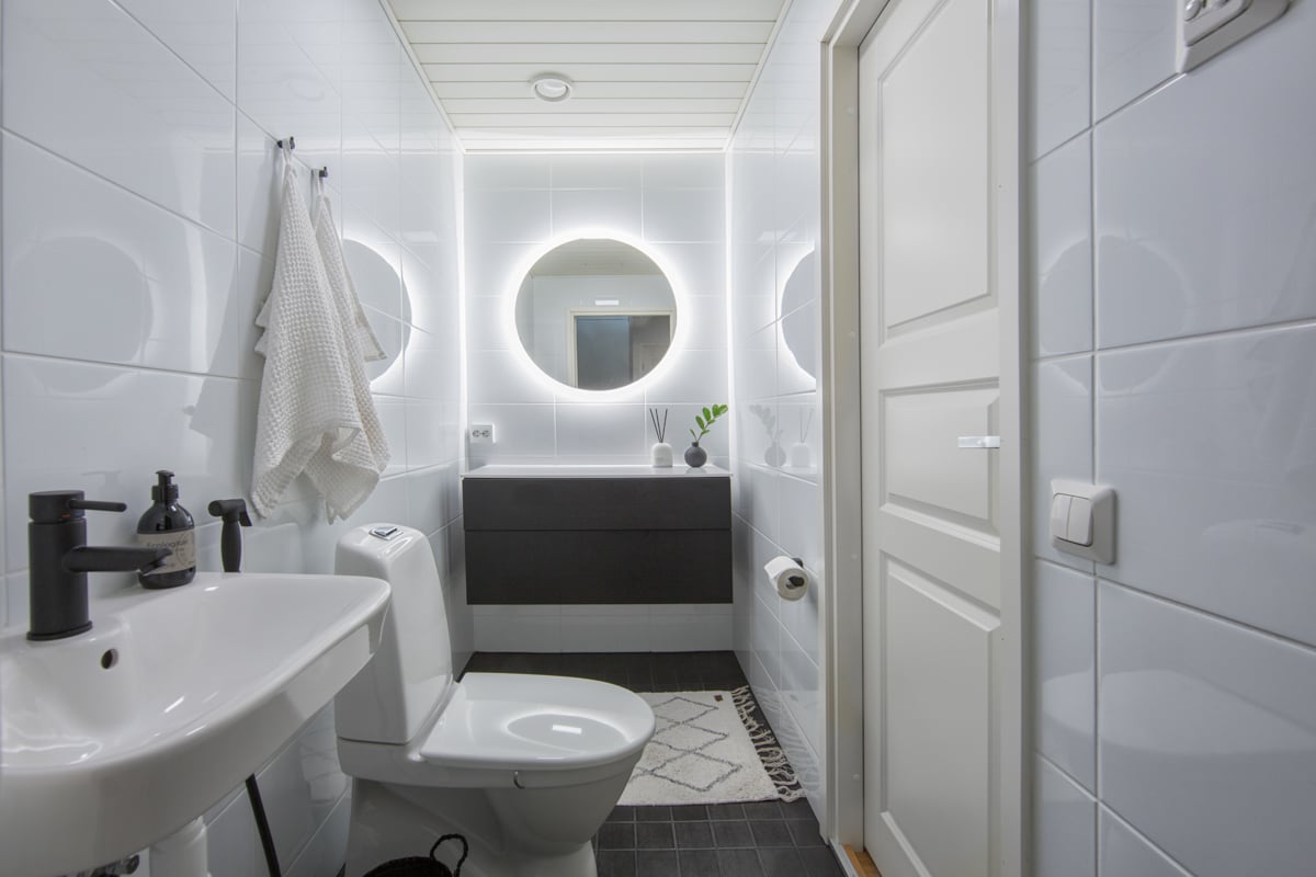 Uusi erillis-WC kiiltävillä seinälaatoilla, tummilla 10x10 lattialaatoilla ja tyylikkäällä valopeilillä.